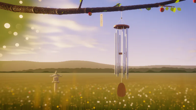 Six aluminium tubes of a wind chime hang from an apple branch in the golden evening light, a paper tanzaku beside them and a stone lantern out in the meadow.