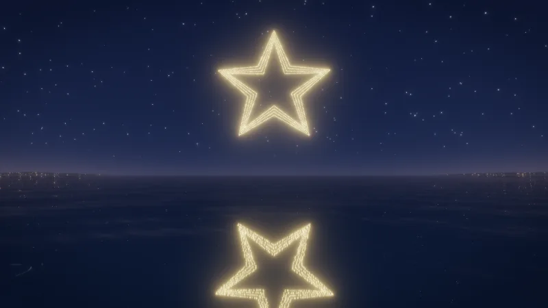 A star drawn by hundreds of drone lights above a dark sea, mirrored in the water.